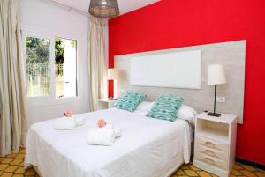 ein Schlafzimmer mit einem weißen Bett mit einer roten Wand in der Unterkunft Villa Maria de Bonaire in Alcanada + 16 Fotos