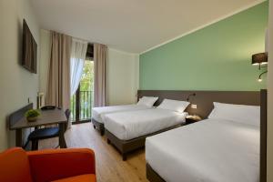 una habitación de hotel con dos camas y una silla en Zenit Park Hotel, en Rivalta di Torino