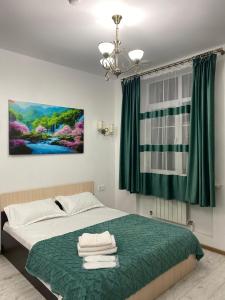 a bedroom with a bed with a green blanket at Adler in Astana