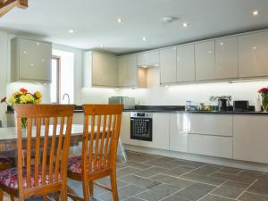 a kitchen with white cabinets and a table and chairs at Slade Barn - Uk42977 in Highbray