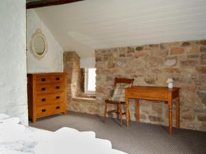 ein Schlafzimmer mit einem Holzschreibtisch und einer Steinwand in der Unterkunft Shire Cottage in Highpeak Junction