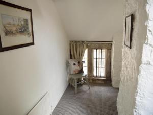 einen kleinen Flur mit einem Stuhl und einem Fenster in der Unterkunft Shire Cottage in Highpeak Junction
