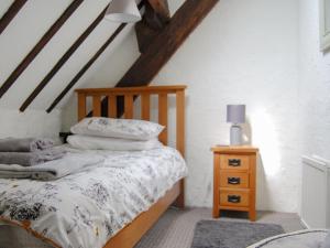 ein Schlafzimmer mit einem Holzbett und einem Nachttisch in der Unterkunft Shire Cottage in Highpeak Junction + 6 Fotos