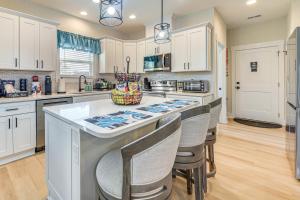 uma cozinha com armários brancos e uma grande ilha com bancos de bar em Hot Tub and Fire Pit Home Near Dtwn Little River! em Little River