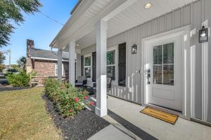 uma casa cinza com uma porta branca e flores em Hot Tub and Fire Pit Home Near Dtwn Little River! em Little River