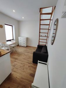 a living room with a black couch and a ladder at Duplex Central Eitorf in Eitorf