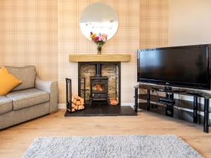 a living room with a fireplace and a flat screen tv at Colbheinn Cottage in Brora