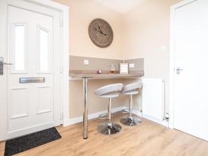 a room with two stools and a clock on the wall at Colbheinn Cottage in Brora
