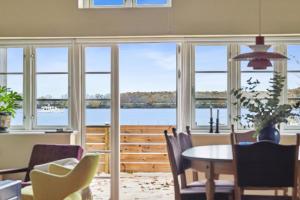 a dining room with a table and chairs and windows at Stråtækt feriehusidyl ved vandet in Sønderborg
