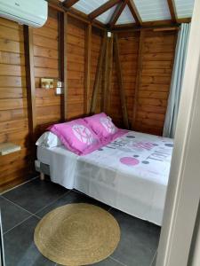 a small bedroom with a bed in a wooden room at Bungalow Capucine in Capesterre-Belle-Eau