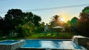 a swimming pool in a yard with a sunset in the background at Y & N BnB in Alberton