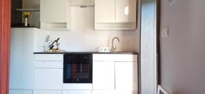 une cuisine avec des armoires blanches et un appareil noir dans l'établissement House Planinka in the heart of nature, à Ljubno 7 autres photos
