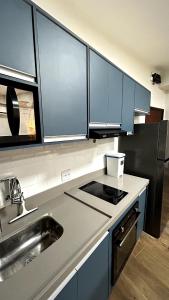 a kitchen with blue cabinets and a sink at Flat Pé na Areia em Angra dos Reis RJ in Angra dos Reis