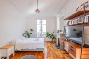 ein weißes Schlafzimmer mit Bett und Flachbildfernseher in der Unterkunft Parisian Escape and Jacuzzi and green Vibes in Paris