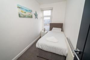 ein kleines Schlafzimmer mit einem Bett und einem Fenster in der Unterkunft Pitchside Comfort – 3-Bed Swansea Home in Morriston