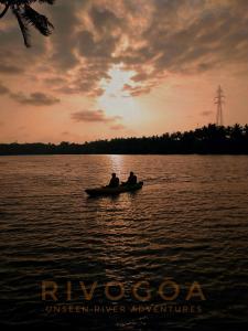 two people in a boat on a lake at sunset at RivoGoa riverside Homestay in Bardez
