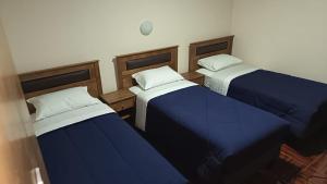 three beds in a room with blue sheets at Lodge Atacama Hostal in Copiapó