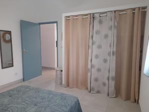 ein Schlafzimmer mit Vorhängen und einem Bett darin in der Unterkunft Le Victoria - 3 pièces in La Possession