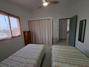 ein Schlafzimmer mit zwei Betten und einem Deckenventilator in der Unterkunft Le Victoria - 3 pièces in La Possession
