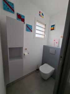 ein weißes Bad mit einem WC und einem Fenster in der Unterkunft Le Victoria - 3 pièces in La Possession