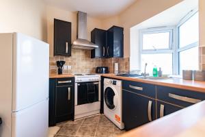 una cucina con armadi neri e una lavatrice/asciugatrice di Stylish 2 Bed Flat with Free Parking near Harbour a Folkestone Altre 43 foto