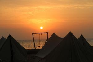 Sonnenuntergang über dem Meer mit einem Basketballkorb am Strand in der Unterkunft Nakhlat E'taal Camp - نخلة التل كامب in Nabq