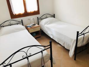 two twin beds in a room with a table at Trilocale I Graniti San Teodoro in Monte Petrosu