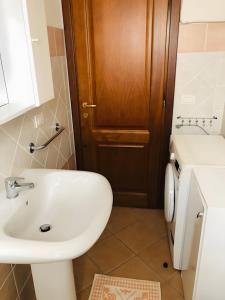 a bathroom with a white sink and a wooden door at Trilocale I Graniti San Teodoro in Monte Petrosu