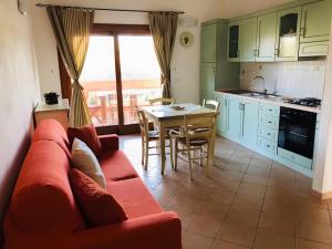 a living room with a red couch and a table at Trilocale I Graniti San Teodoro in Monte Petrosu +11 photos