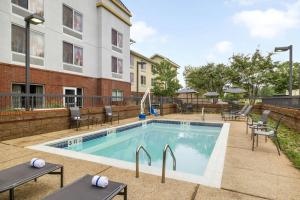 une piscine avec des chaises et un bâtiment dans l'établissement Fairfield Inn & Suites Memphis Olive Branch, à Olive Branch