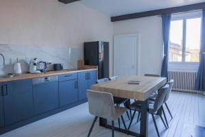 a kitchen with a wooden table and blue cabinets at Les Haussmanniens in Pont-de-Vaux +19 photos
