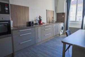 a large kitchen with white cabinets and a table at Les Haussmanniens in Pont-de-Vaux