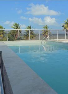 einen Pool mit blauem Wasser und Palmen in der Unterkunft Puerto Ventura 403 · Puerto Ventura - Beira Mar na Orla de Cabo Branco in Tambaú