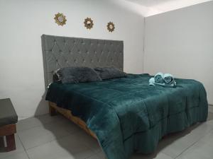 une chambre avec un lit vert sur lequel se trouvent deux paires de chaussures dans l'établissement Cómoda habitación, à Pátzcuaro