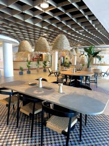 a restaurant with tables and chairs and potted plants at Canvas Sevilla Lago in Seville
