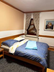 a bedroom with a bed with blue sheets and a window at Baroko Rooms & Apartments in Varaždin