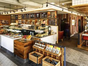 una panadería con una persona de pie detrás de un mostrador en ibis Cambridge Central Station, en Cambridge