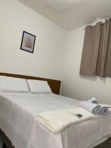 a bedroom with a white bed with towels on it at Pousada Central in Buíque