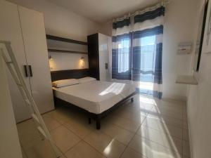 ein Schlafzimmer mit einem Bett und einem großen Fenster in der Unterkunft Residence Equilio Family Apartments in Lido di Jesolo + 19 Fotos