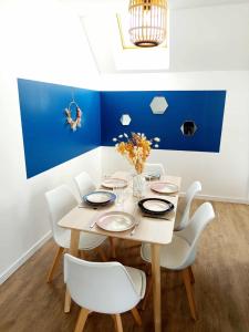a dining room with a wooden table and white chairs at Escapade, T3 Proche gare in Cholet