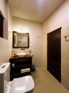 ein Badezimmer mit Waschbecken, Toilette und Spiegel in der Unterkunft House of Merchants in Galle