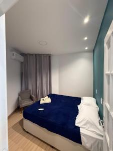 um quarto com uma cama azul e uma cadeira em Apartamento no Centro RJ - Rua do Theatro Municipal no Rio de Janeiro mais 5 fotografias