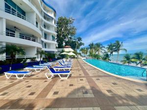 a resort swimming pool with lounge chairs and the ocean at Encantador estudio frente al mar en Coronado Bay in Las Lajas