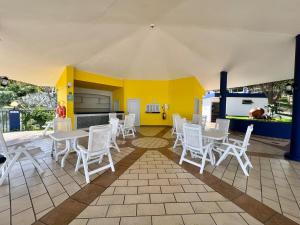 a room with white tables and chairs and a kitchen at Encantador estudio frente al mar en Coronado Bay in Las Lajas