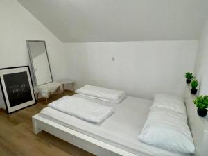 Una habitación blanca con dos camas y un espejo. en ModernLoft Ried, Balcony Suite, en Neuhofen im Innkreis