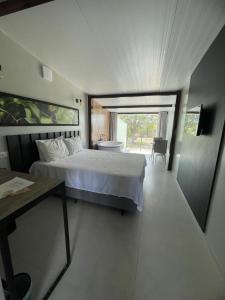 a bedroom with a bed and a table and a window at Suítes Domo do Matto in Garanhuns