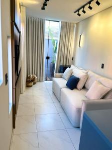 a living room with a white couch with pillows at ECOLETRAS LOFT CONTAINER - SÃO THOMÉ DAS LETRAS Mg in São Thomé das Letras