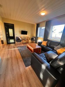 a living room with a black leather couch and a table at Hlíðarból Guesthouse in Hvolsvöllur