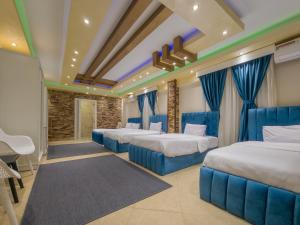 a hotel room with four beds and blue drapes at Villa 53 Hotel Luxury Suites by Pharaohs Hospitality in Sheikh Zayed