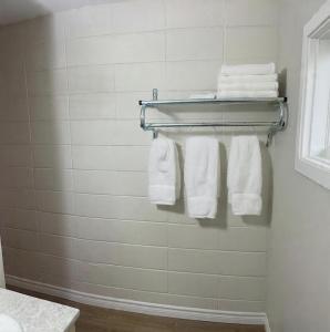 une salle de bain avec des serviettes blanches accrochées à un porte-serviettes dans l'établissement Inn On Pim, à Sault-Sainte-Marie